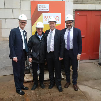 Andreas Dracopoulos, co-president of the Stavros Niarchos Foundation, and three other men stand with construction hats at the Parkway Theatre